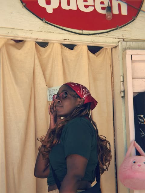 Candid portrait beneath a vintage Queen sign